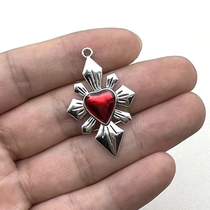 Gothic starburst pendant with a red heart center displayed on a hand with white background