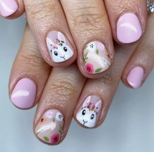 Close-up of Easter bunny nail art stickers with pink floral patterns on fake nails