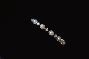 Macro shot of minimalist gold ring featuring a white pearl and small sparkling zircons