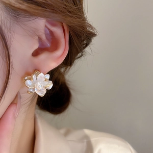 Close-up of pearl flower earrings worn by a model in soft warm natural lighting