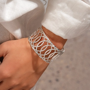 Gros plan d'un bracelet ouvert argenté au design géométrique circulaire évidé multicouche
