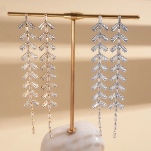 Detailed view of silver needle tassel earrings with zircon leaf design in gold and silver