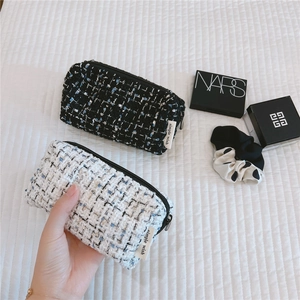 Macro view of woven tweed makeup pouches in black and white with simple wish woven label