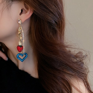 Close-up of long tassel earrings with sparkling strawberry and blue heart charms