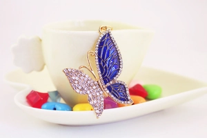 Detail of a golden butterfly keychain featuring blue enamel and sparkling rhinestones