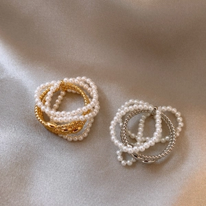 Elegant multi-layer pearl open rings in gold and silver finish on champagne silk fabric