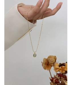 Detail of 18k gold-plated satellite chain featuring a green oval cat-eye stone pendant