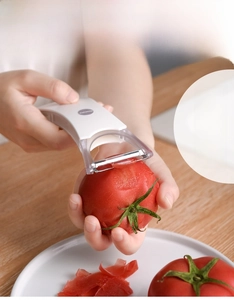 Dual-head peeler removing tomato skin on a wooden table with high-quality detail view
