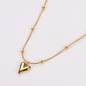 Detail of a gold-plated heart pendant on a stylish snake chain with small golden beads