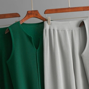 Close-up of green sleeveless knit top with vertical ribbed texture on a wooden hanger