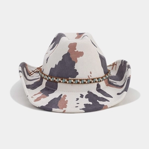 Detail of western cowboy hat featuring cow print pattern and turquoise beaded hatband