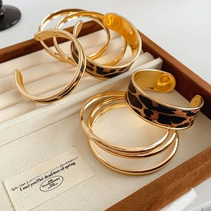 Détail d'un ensemble de bracelets dorés avec cuir léopard dans un écrin à bijoux