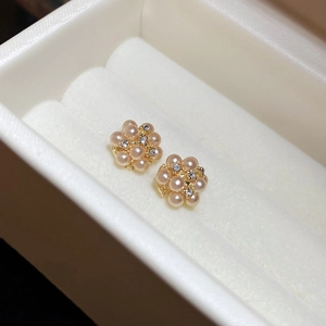 Detail of flower-shaped pearl earrings with gold plating and zircons on velvet