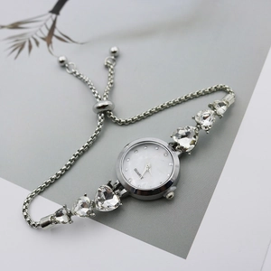 Detail of silver bracelet watch featuring heart-shaped crystals and a minimalist dial