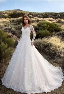 Exquisite white lace long sleeve wedding dress with sheer floral neckline and a large train