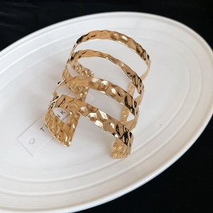 Macro shot of gold hammered texture metal bracelet with layered hollow wave design