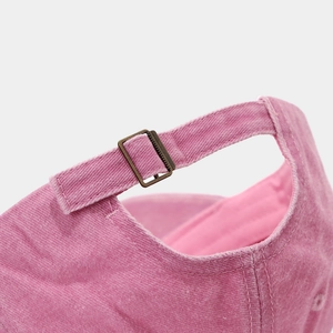 Close-up of pink washed cotton baseball cap featuring adjustable vintage metal buckle