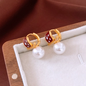 Detail view of ladybug pearl earrings featuring red enamel and gold-plated finish