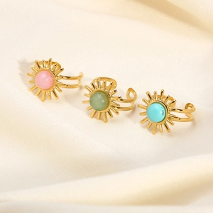 Three vintage turquoise sun rings in gold finish displayed on beige silk texture