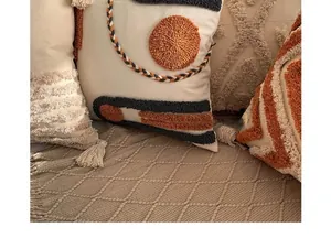 Close-up of bohemian tufted cushion covers with orange woven patterns and tassels