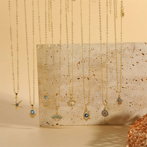 Goldene Hamsa-Hand und Evil Eye Anhänger Halsketten mit blauen Zirkonia auf Stein-Hintergrund