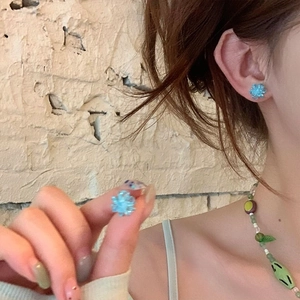 Detail of blue flower stud earring in resin featuring a refreshing summer floral design
