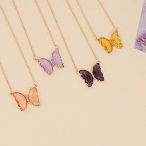 Detail of colorful glass butterfly pendants on fine metal chains in gold-plated frames