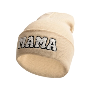 Detailed close-up of MAMA towel embroidery on a beige knitted beanie hat