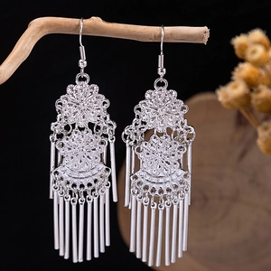 Close-up of vintage silver floral earrings with metal tassels hanging on a branch