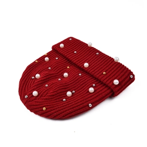 Dettaglio del berretto in maglia rossa con perle finte e perline metalliche lucide
