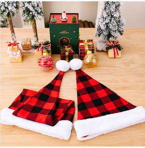 Flat lay of red and black buffalo plaid Christmas hats with plush trim on a festive wooden desk