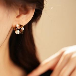 Close-up of vintage gold hoop earrings featuring amber beads and white pearls on ear
