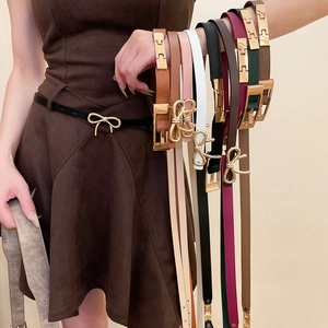 Close-up of vintage leather skinny belts in multiple colors with gold bow buckles