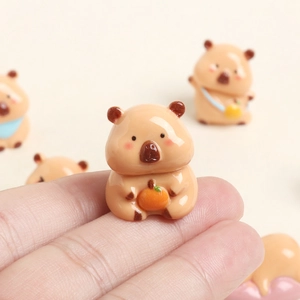 Cute resin Capybara miniature holding an orange fruit shown on a fingertip