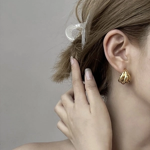 Close-up of triple-layered golden C-shaped hoop earrings on female model