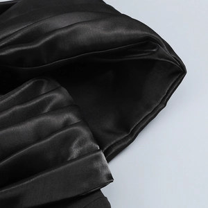 Detail of elegant black pleated fabric with a glossy silk finish on an evening gown