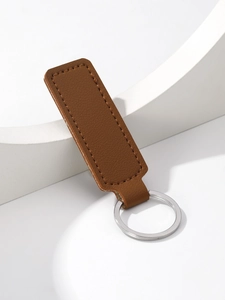 Detail of brown leather rectangular keychain with silver ring and stitching on white stand
