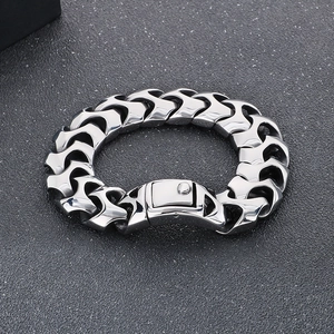 Detail view of chunky silver punk chain bracelet with industrial snap buckle on stone texture