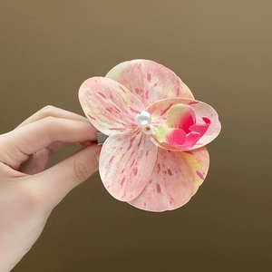 Detail of pink orchid hair claw clip with yellow petals and a pearl center accent