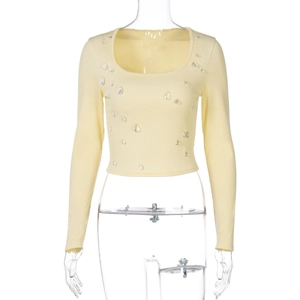 Dettaglio del top a maglia a coste giallo chiaro con strass decorativi a forma di goccia d'acqua