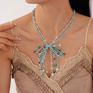 Detailed view of layered blue and silver bead necklace with crystal bow pendant on model