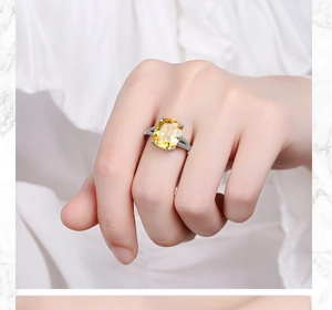 Close-up of women's wide silver ring featuring a large yellow cushion-cut zircon stone