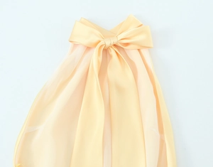 Détail de la robe midi en satin champagne avec un grand nœud décoratif et un col plissé