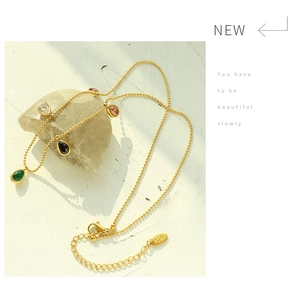 Detail of 18K gold teardrop necklace with colorful stones and K18 hallmark tag