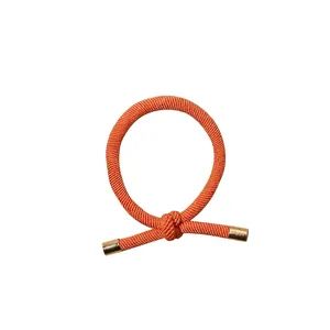 Knotted elastic hair tie in vibrant orange with elegant gold metal tips for women