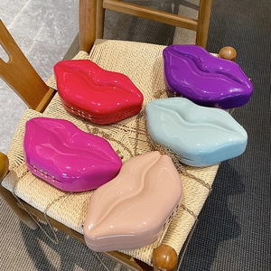 Lip-shaped acrylic chain bags in five vibrant colors displayed on a stylish wooden chair