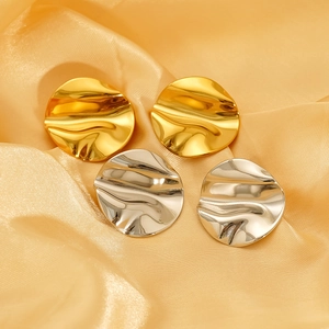 Macro shot of irregular pleated metal earrings in gold and silver on silk fabric