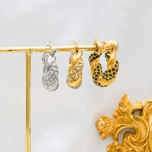 Macro shot of 18K gold and silver twisted C-hoop earrings with sparkling zircon stones