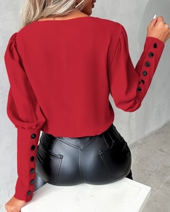 Detailed back view of red puff sleeves featuring elegant black decorative button cuffs