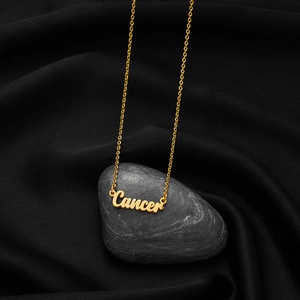 Macro shot of gold Cancer zodiac necklace pendant on a luxury black satin background